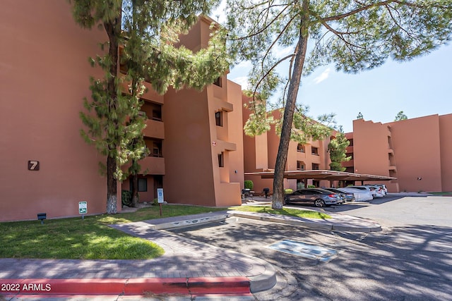 view of property featuring covered and uncovered parking