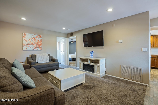 living room with a glass covered fireplace, visible vents, and recessed lighting