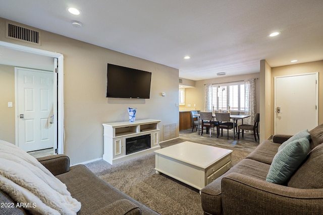 living area with carpet flooring, a glass covered fireplace, visible vents, and recessed lighting