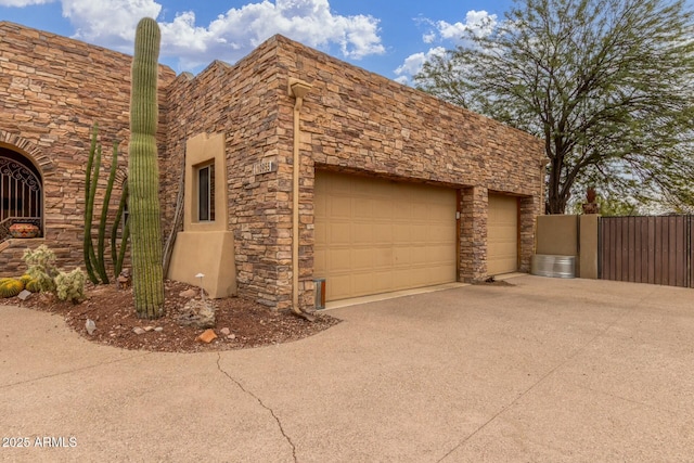 view of home's exterior featuring an attached garage, stone siding, and driveway