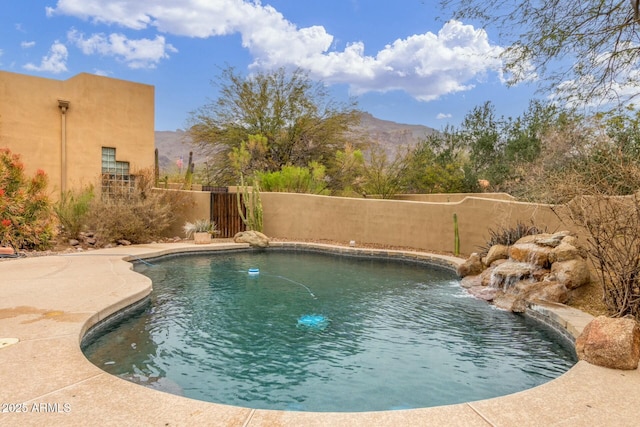 view of swimming pool with fence and a mountain view