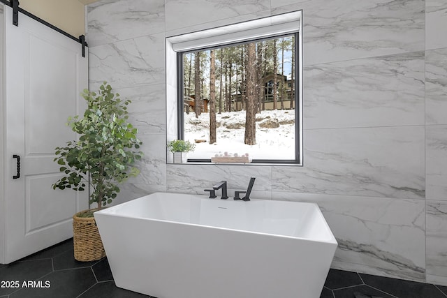 bathroom with a bathing tub, tile patterned flooring, and tile walls