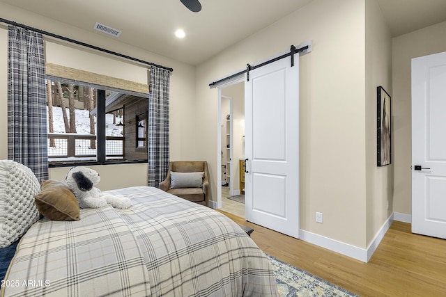 bedroom with hardwood / wood-style flooring and a barn door