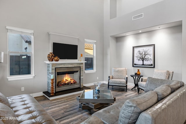 living room featuring hardwood / wood-style floors, a stone fireplace, and a towering ceiling