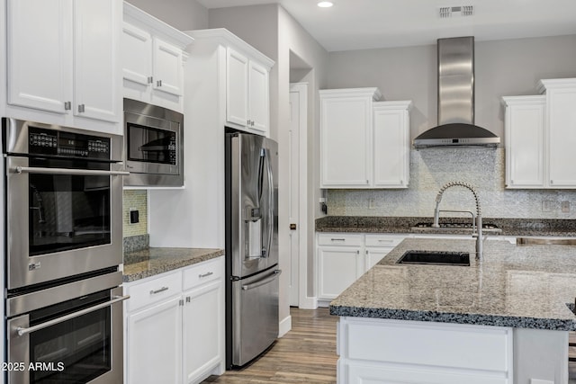 kitchen with white cabinetry, appliances with stainless steel finishes, and wall chimney range hood