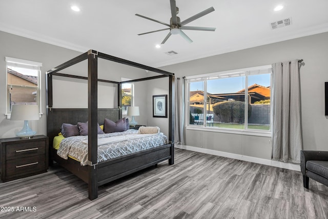 bedroom with multiple windows, crown molding, and hardwood / wood-style floors