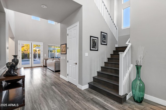 staircase featuring wood-type flooring, french doors, and a high ceiling