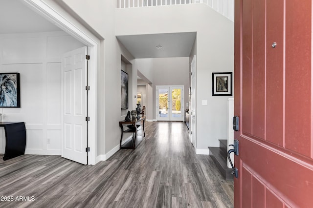 foyer entrance featuring dark wood-type flooring, french doors, and a high ceiling