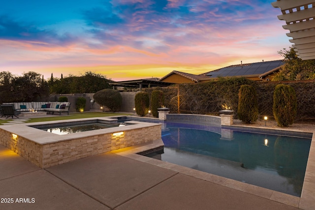 pool at dusk featuring an outdoor living space, an in ground hot tub, and a patio area