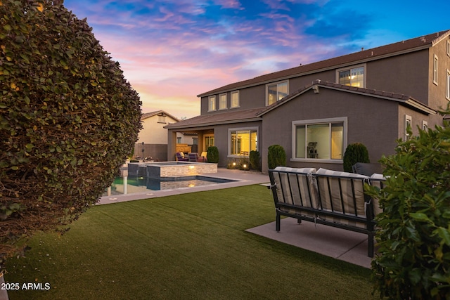 back house at dusk featuring a swimming pool with hot tub, an outdoor hangout area, a lawn, and a patio area