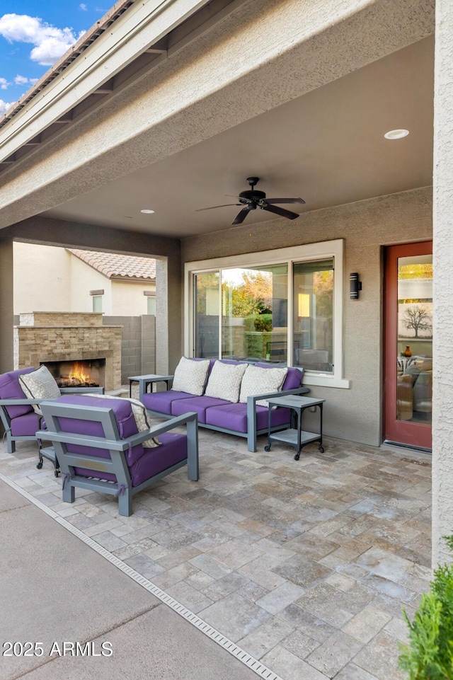 view of patio / terrace featuring an outdoor living space with a fireplace and ceiling fan