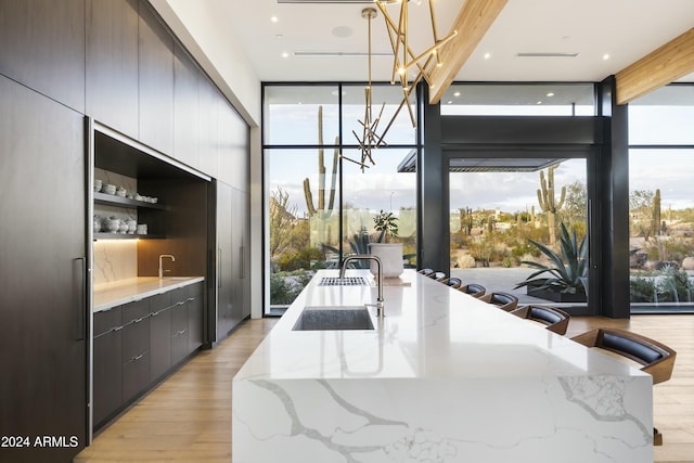 kitchen with expansive windows, light stone counters, an inviting chandelier, and pendant lighting