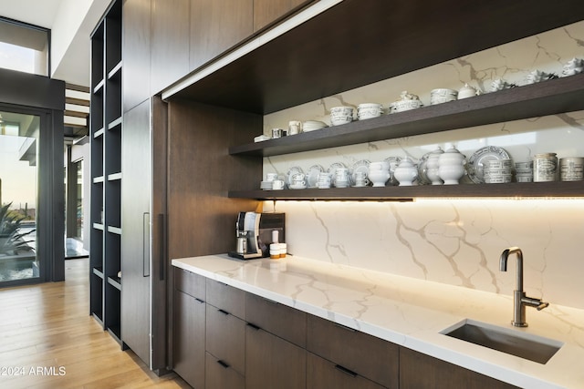 bar featuring tasteful backsplash, a sink, and light wood finished floors