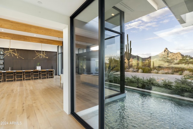 doorway featuring light wood-style flooring, a mountain view, a wall of windows, and a notable chandelier