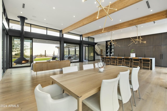 dining room featuring visible vents, light wood-style flooring, a wood stove, stairs, and floor to ceiling windows