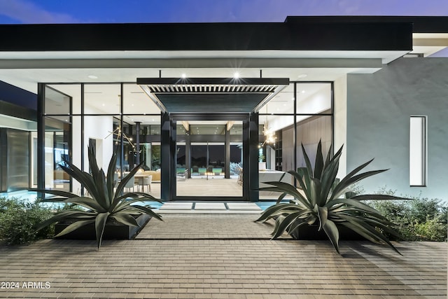 exterior entry at dusk featuring stucco siding