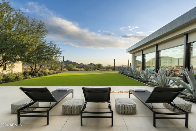 patio terrace at dusk with a yard and a mountain view