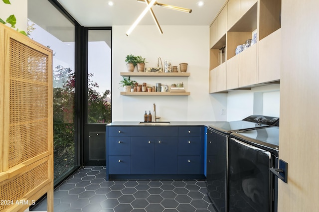 kitchen featuring dark tile patterned flooring, a sink, washer and dryer, blue cabinetry, and open shelves