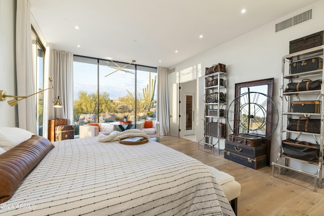 bedroom featuring light wood-style flooring, visible vents, a wall of windows, and recessed lighting