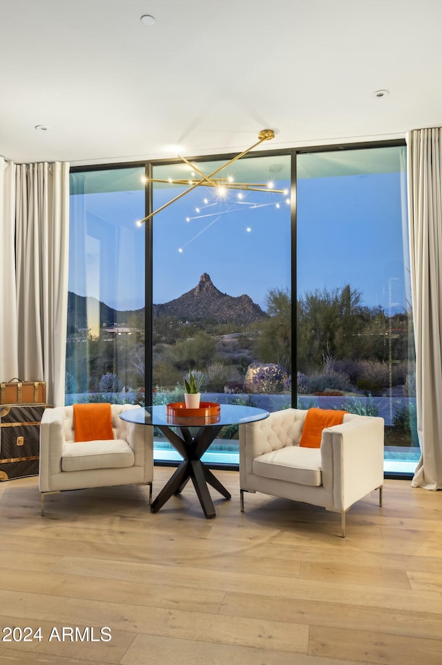 living area with a healthy amount of sunlight, light wood finished floors, a mountain view, and a wall of windows