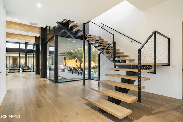 staircase featuring a healthy amount of sunlight, floor to ceiling windows, visible vents, and wood finished floors