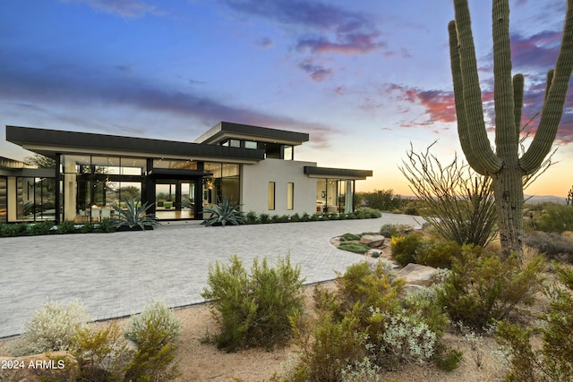 rear view of property with decorative driveway and stucco siding