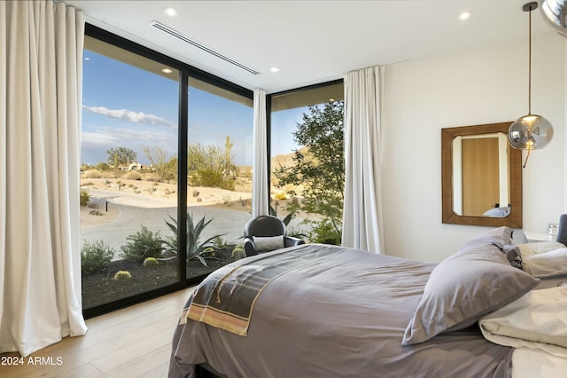 bedroom featuring a wall of windows, access to outside, light wood-type flooring, and recessed lighting