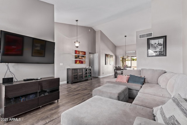 living area featuring baseboards, wood finished floors, visible vents, and high vaulted ceiling