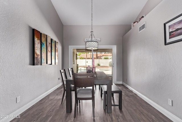 dining space with dark wood-type flooring, a textured wall, visible vents, and baseboards
