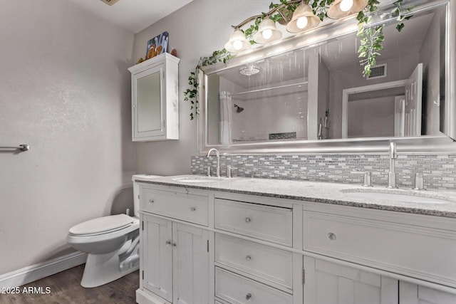 bathroom featuring backsplash, visible vents, toilet, and a sink