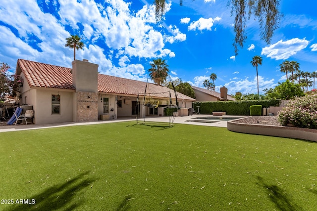 rear view of house with a tile roof, a patio, a chimney, and stucco siding