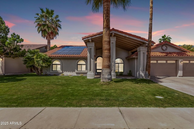 mediterranean / spanish home with a tile roof, concrete driveway, a garage, roof mounted solar panels, and stucco siding