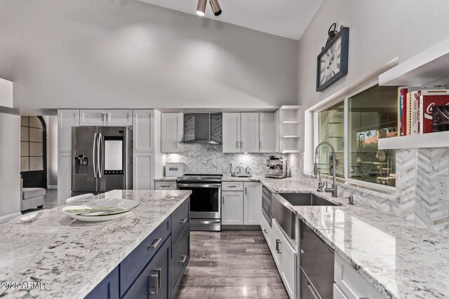 kitchen featuring stainless steel appliances, open shelves, wall chimney range hood, light stone countertops, and white cabinetry