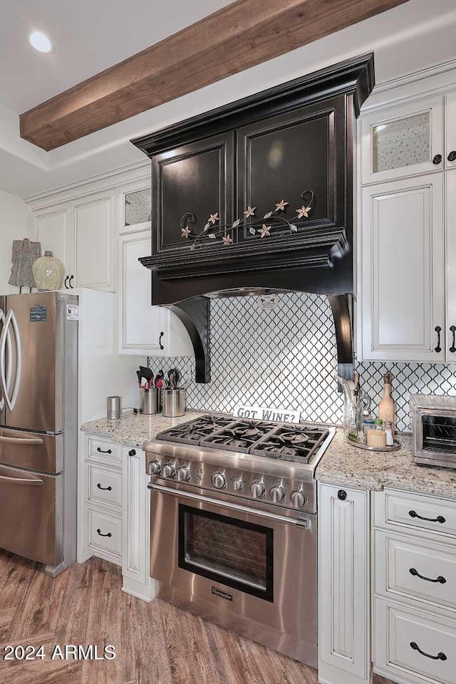 kitchen featuring backsplash, white cabinetry, light hardwood / wood-style flooring, and stainless steel appliances