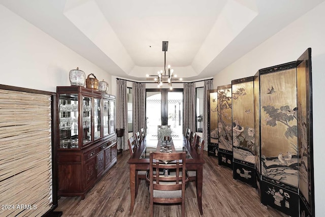 dining space featuring a tray ceiling, dark hardwood / wood-style flooring, and a chandelier