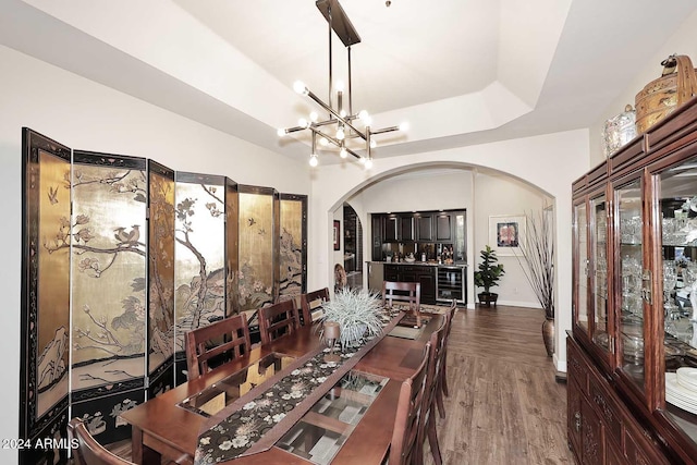 dining area with a tray ceiling, a chandelier, and hardwood / wood-style flooring