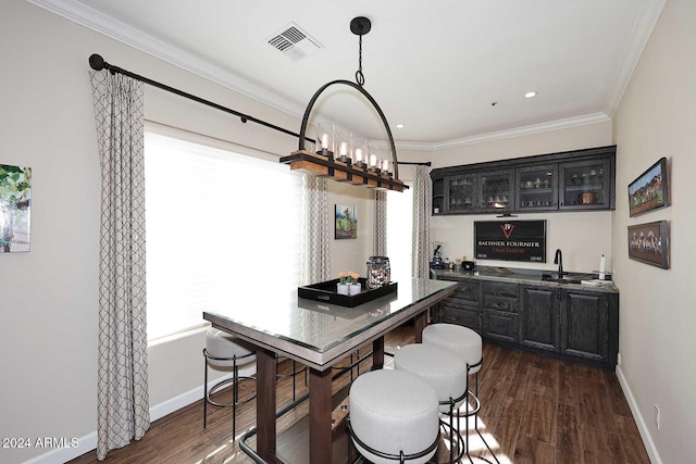 dining area with ornamental molding, dark wood-type flooring, and bar area