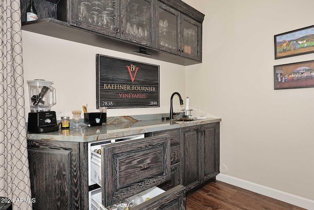 bar featuring dark hardwood / wood-style flooring, dark brown cabinets, and sink