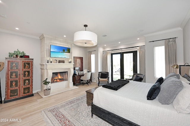 bedroom with crown molding, a fireplace, light hardwood / wood-style floors, and french doors