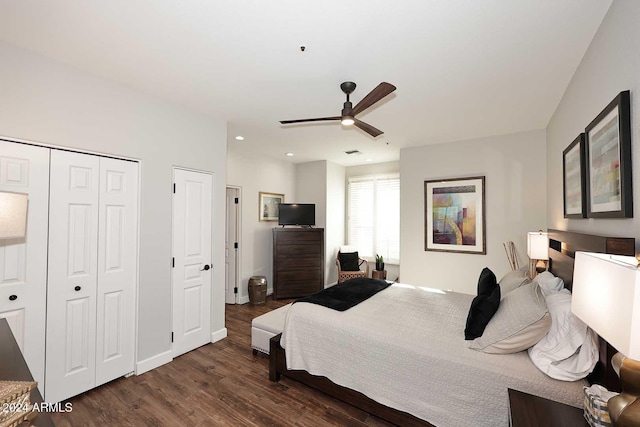 bedroom with ceiling fan, dark hardwood / wood-style flooring, and two closets