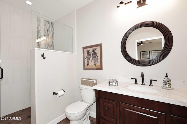 bathroom featuring hardwood / wood-style flooring, toilet, a tile shower, and vanity