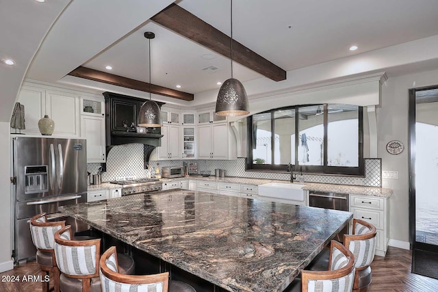 kitchen with appliances with stainless steel finishes, dark parquet floors, a spacious island, sink, and white cabinetry