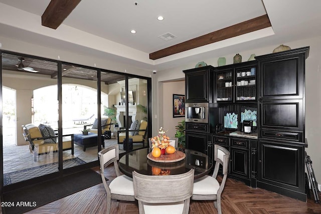 dining space featuring dark parquet floors, beam ceiling, and a tray ceiling