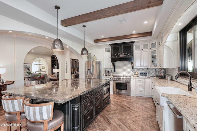 kitchen with pendant lighting, tasteful backsplash, a kitchen island, stainless steel appliances, and light parquet flooring