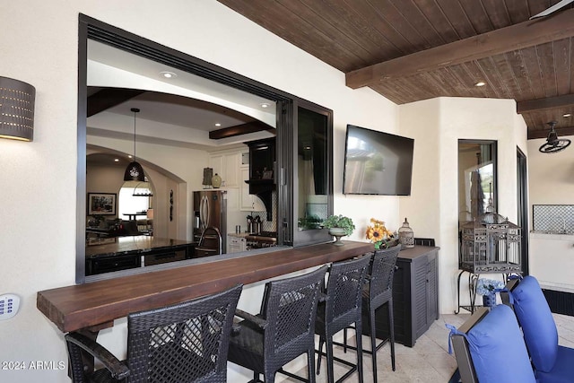 bar with stainless steel fridge, wood ceiling, pendant lighting, beamed ceiling, and light tile patterned flooring