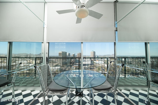 unfurnished sunroom featuring a healthy amount of sunlight, a view of city, and a ceiling fan