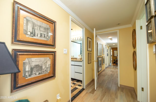 hallway with crown molding, baseboards, and light wood finished floors