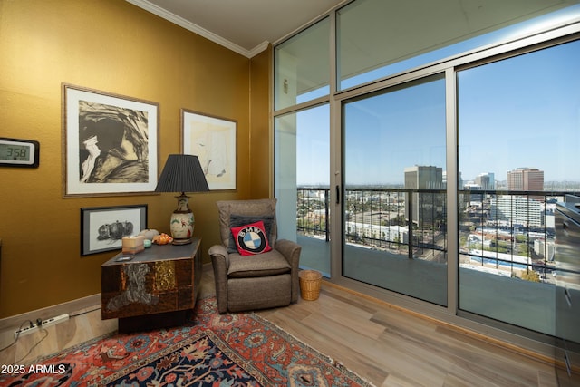 sitting room featuring a wall of windows, wood finished floors, a city view, and ornamental molding