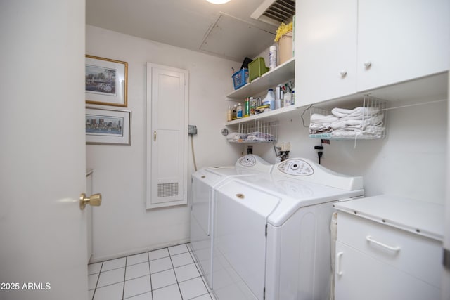 clothes washing area with washing machine and clothes dryer, light tile patterned floors, and cabinet space