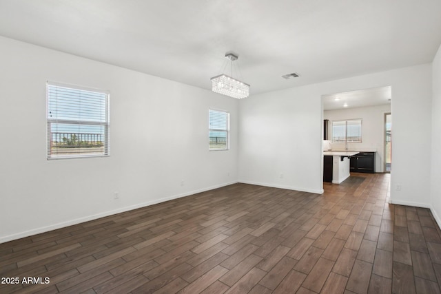 empty room featuring a chandelier and a wealth of natural light